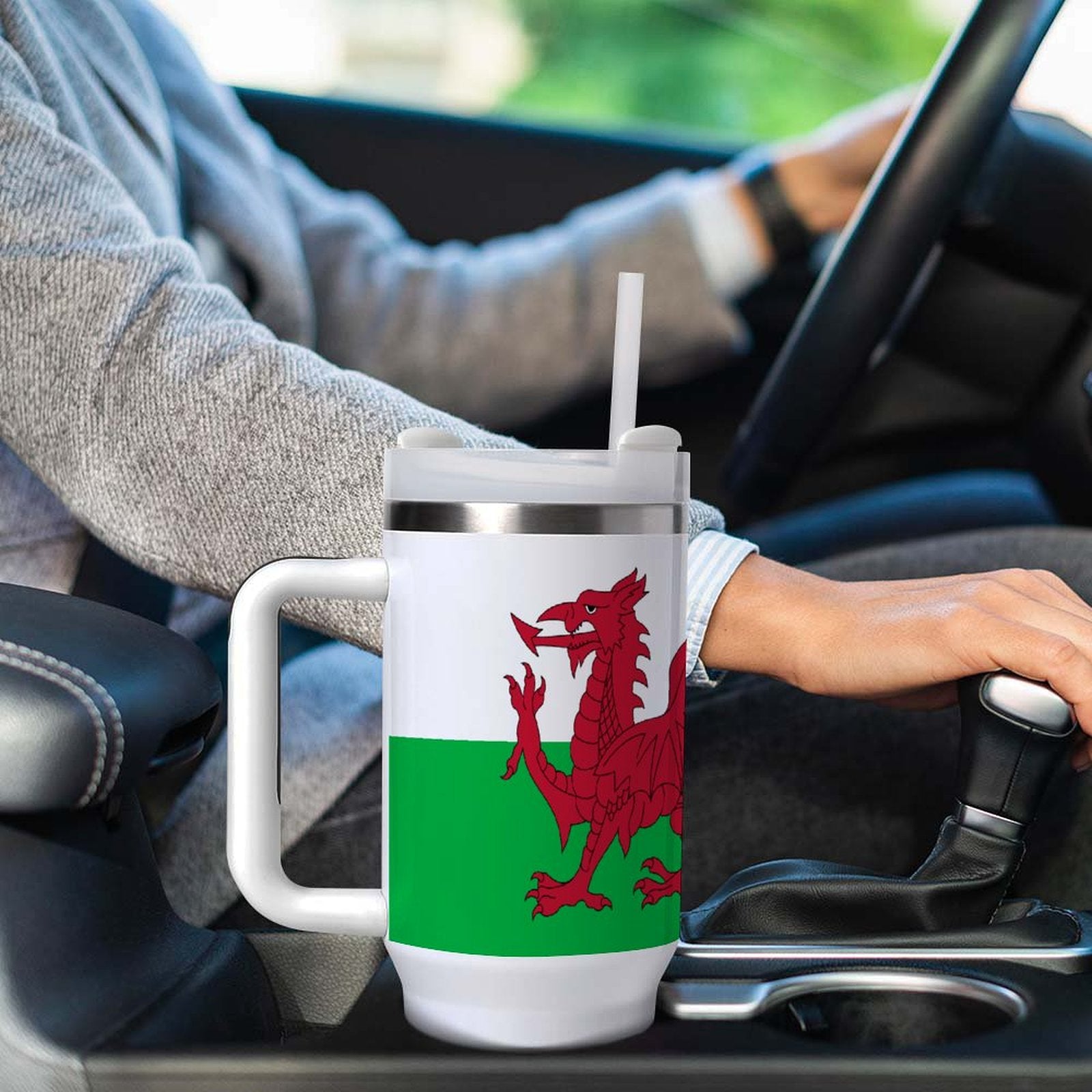 Driver holding [Brand] travel mug with Welsh flag design.