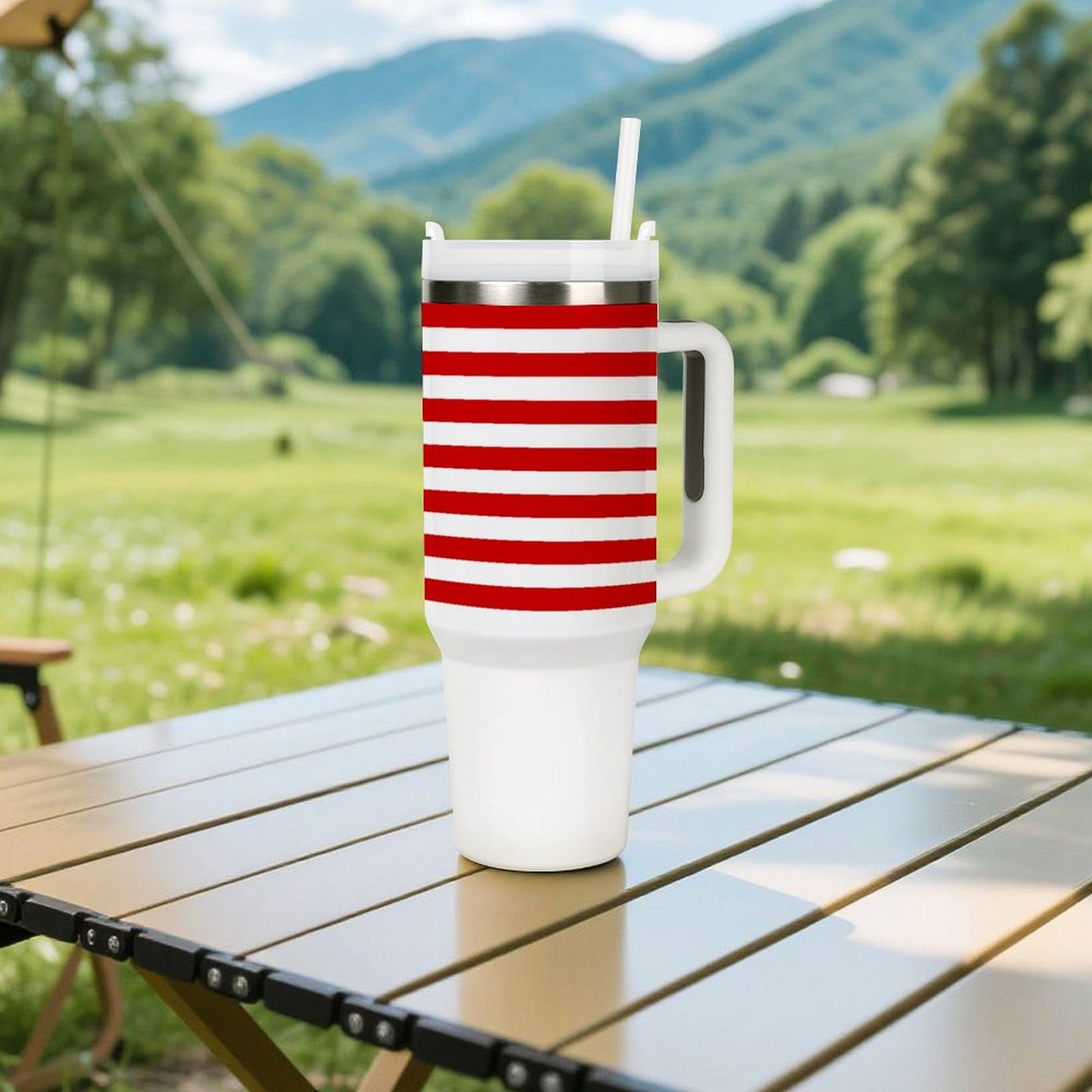 [Brand] striped mug with straw outdoors on table, mountains background.