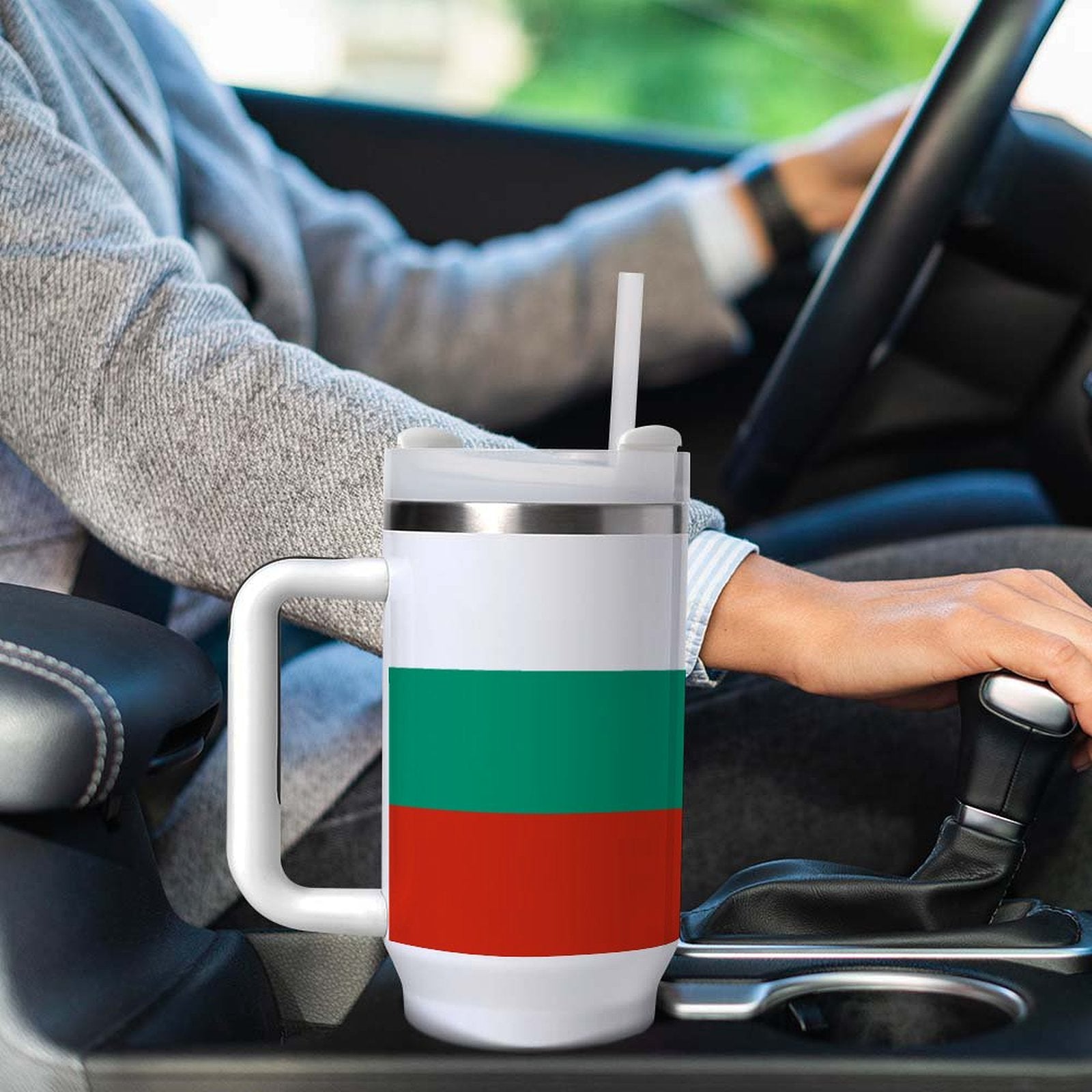 Person drives with [Brand] mug in cup holder; colorful design.