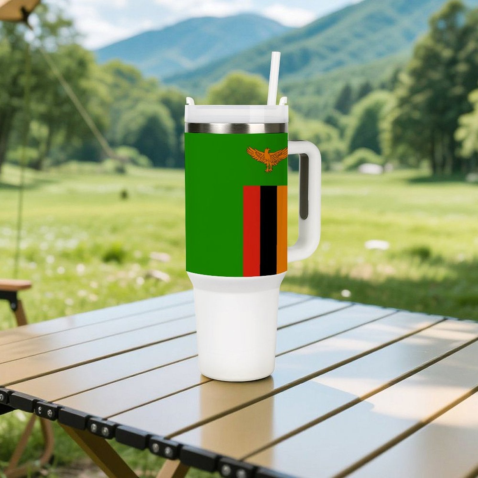 [Brand] travel mug with Zambian flag on picnic table.