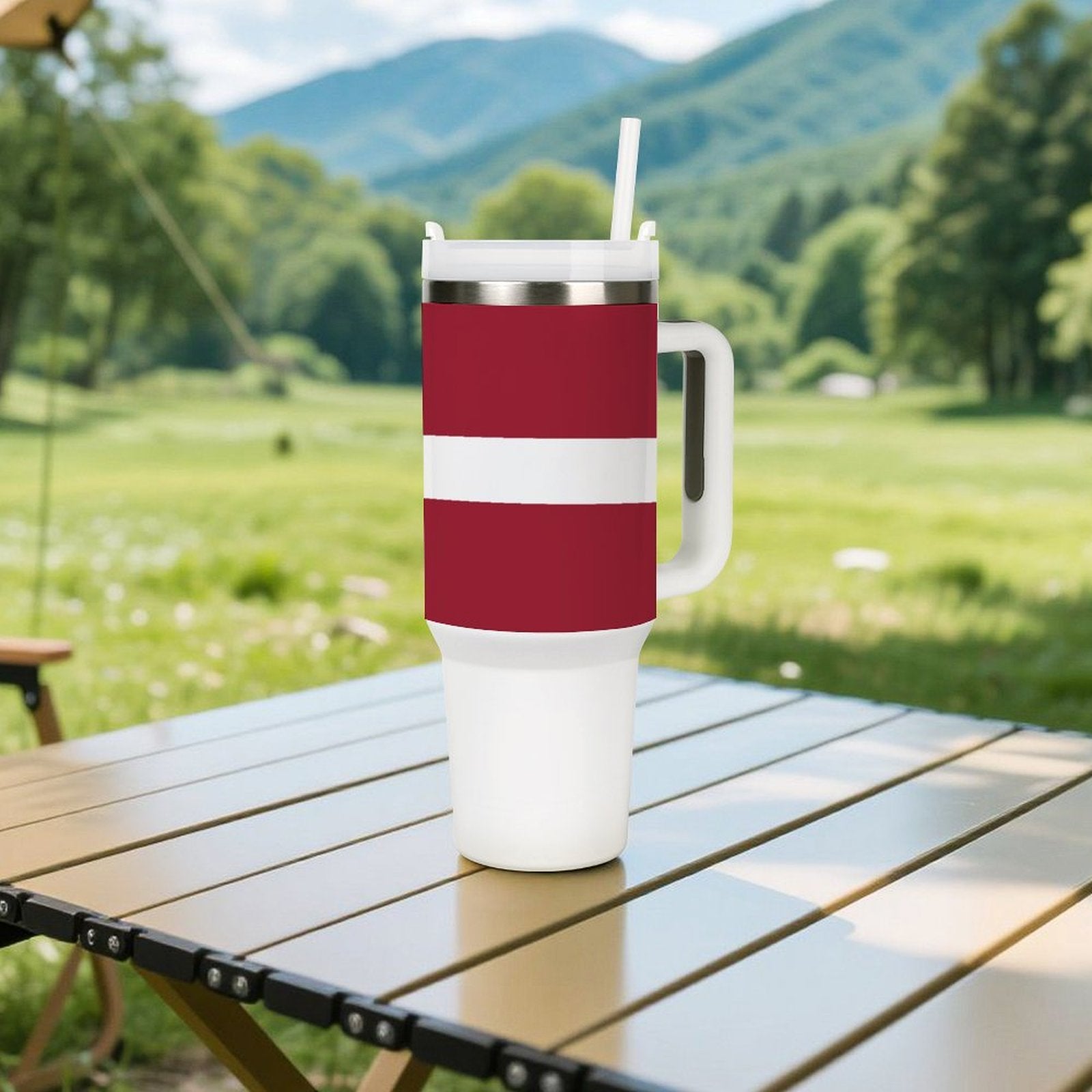 [Brand] tumbler on picnic table with scenic mountain backdrop.