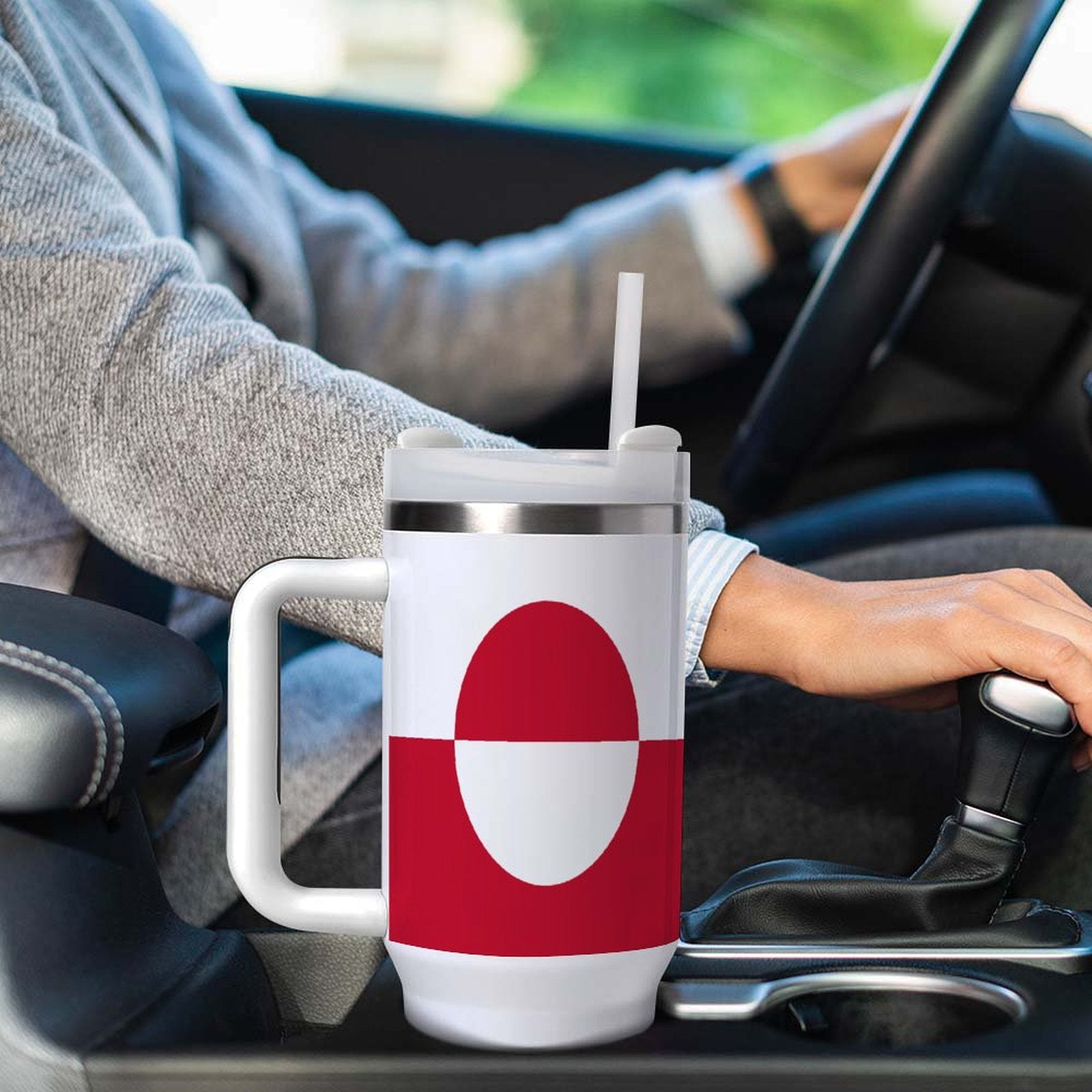 Person driving with [Brand] mug in car cup holder.