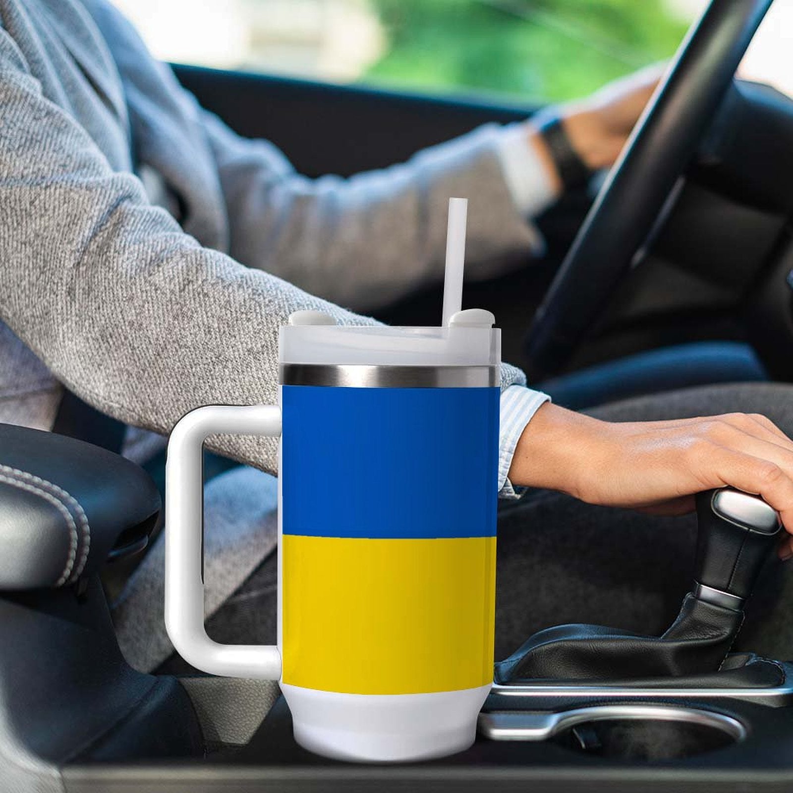 Hand on gearshift with [Brand] cup in car holder.