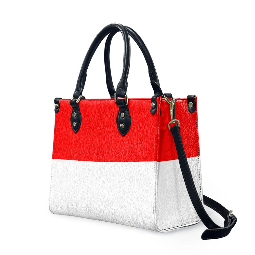 Red and white [Brand] handbag with black handles and strap.