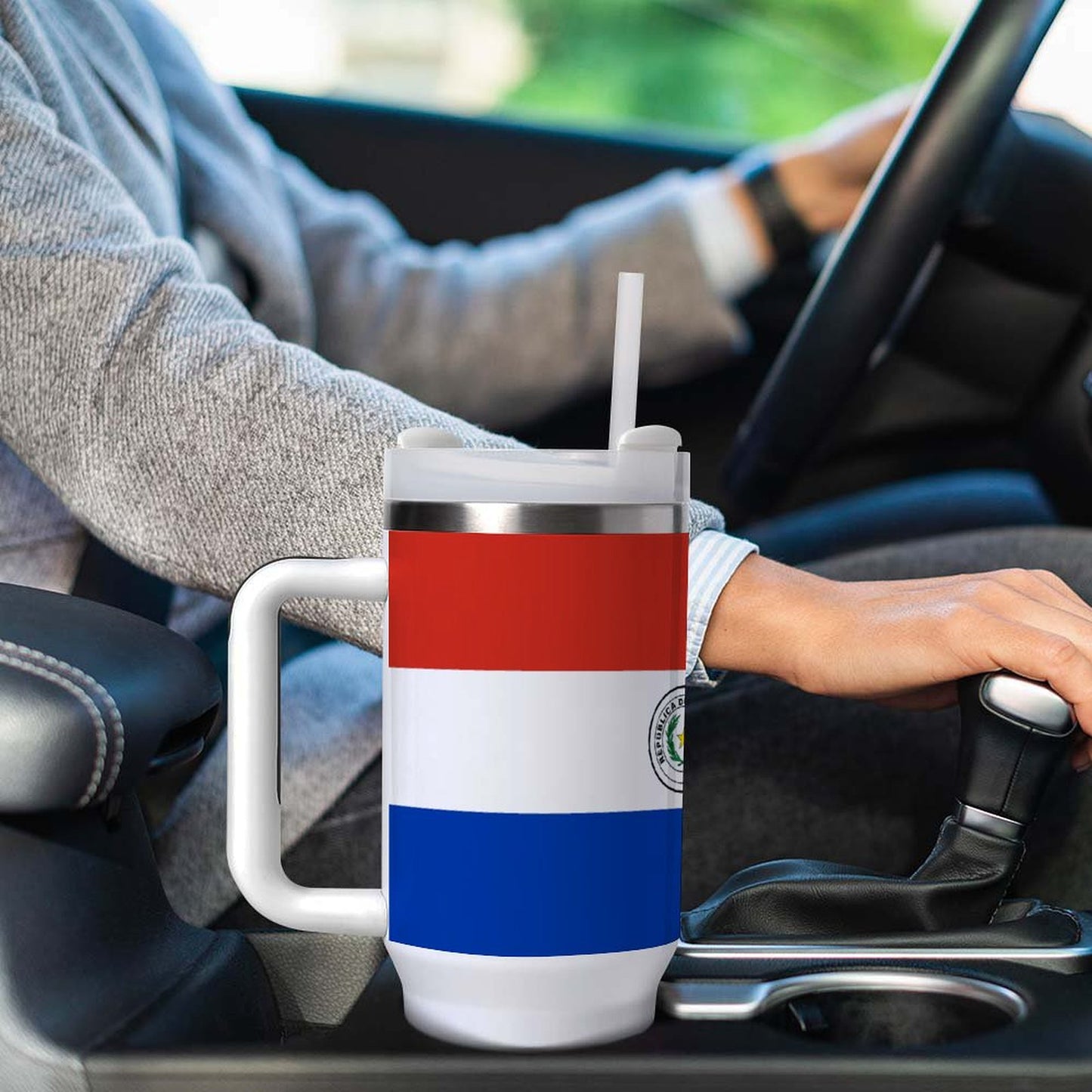 Person driving with [Brand] mug in car cup holder.