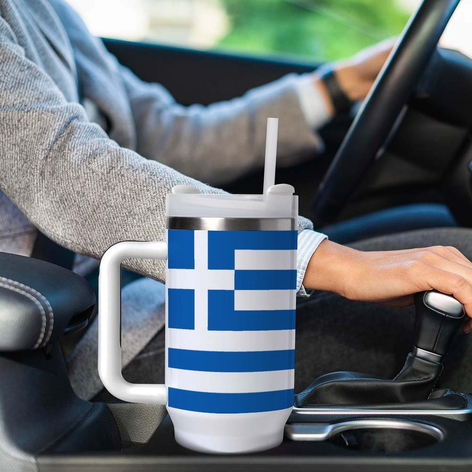 Person driving with [Brand] mug featuring Greek flag design.