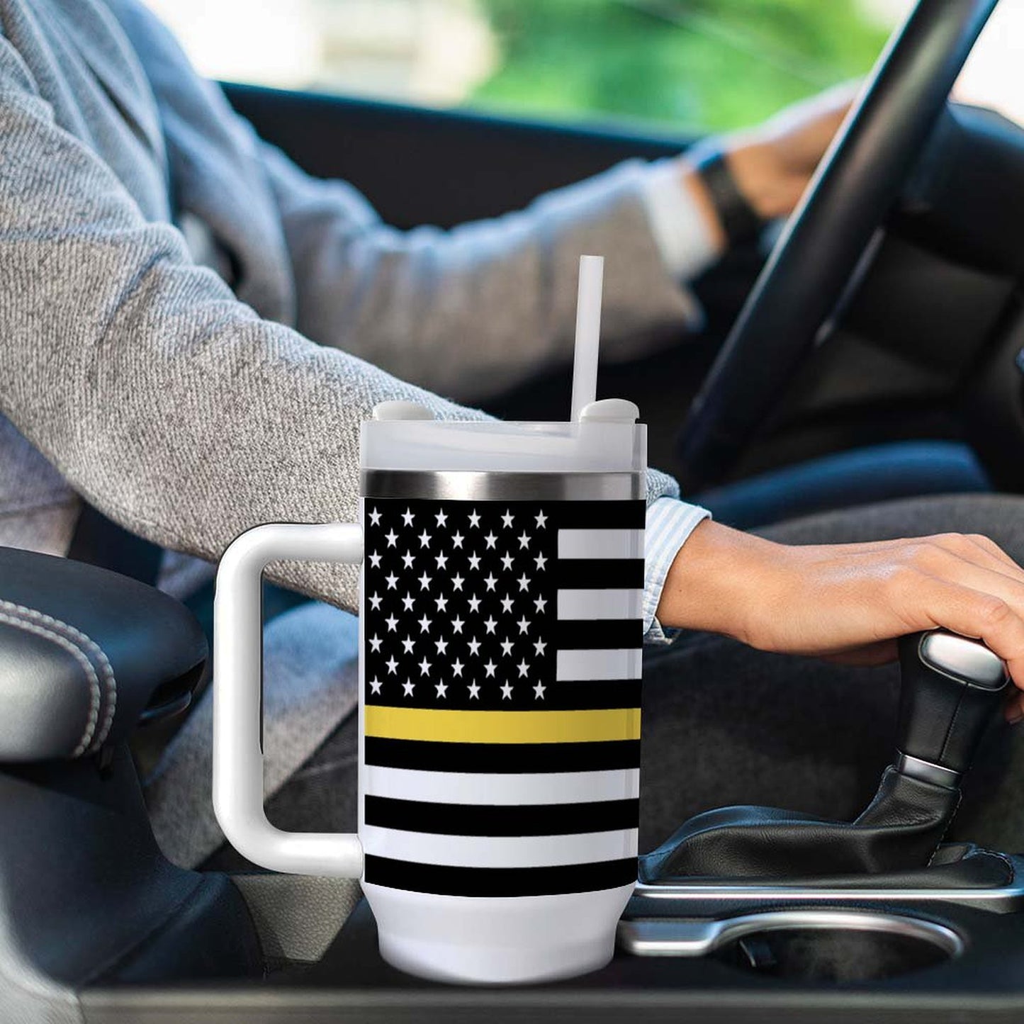 Driver holds [Brand] mug with American flag design inside car.