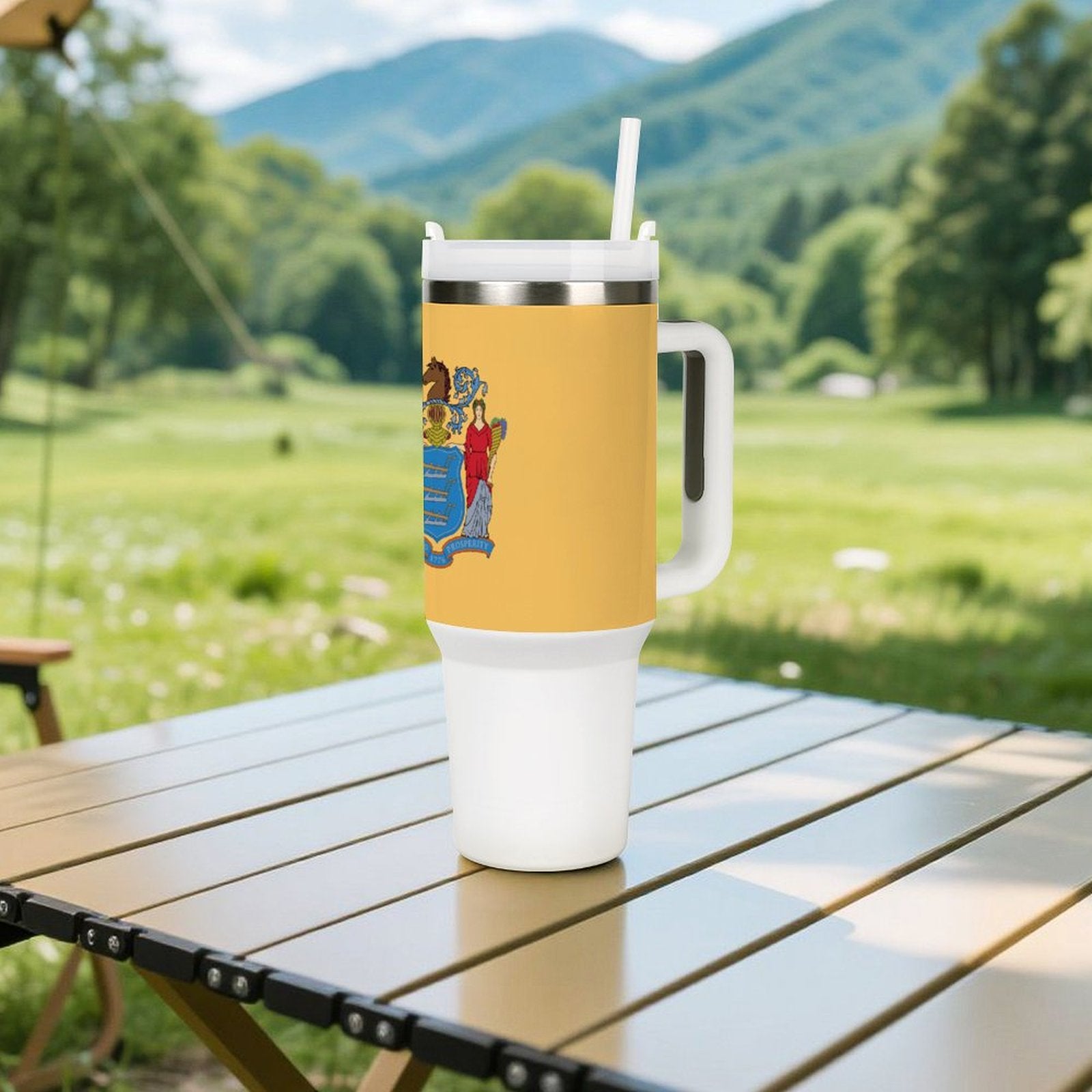 Yellow [Brand] tumbler on table, scenic mountains in background.
