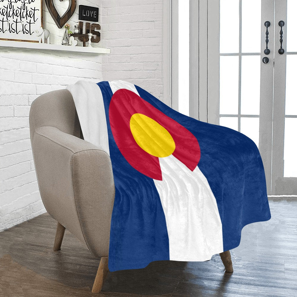 Cozy chair with Luv My Flag Colorado-themed blanket draped.