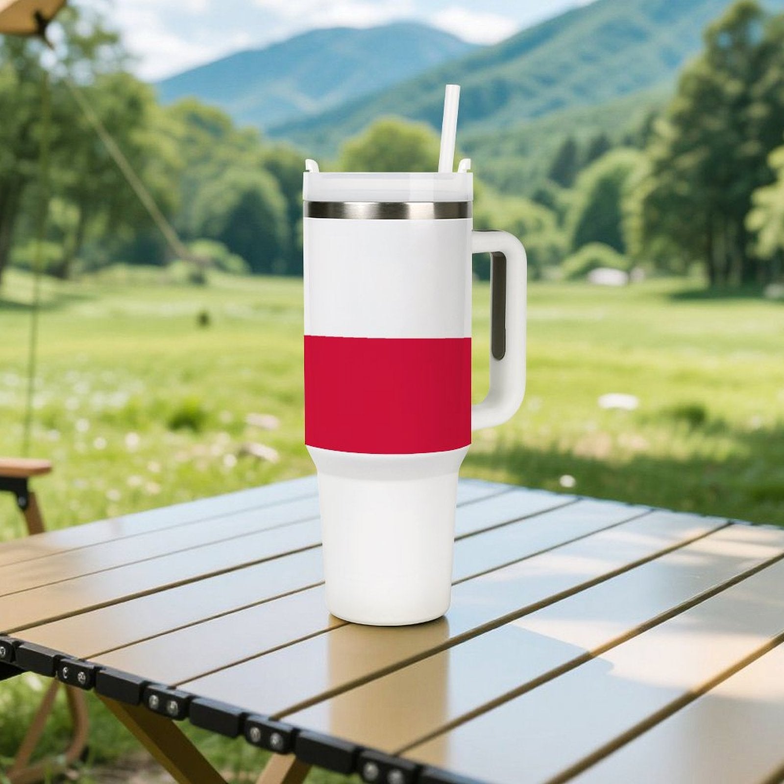 [Brand] tumbler with red stripe on outdoor table, mountains.