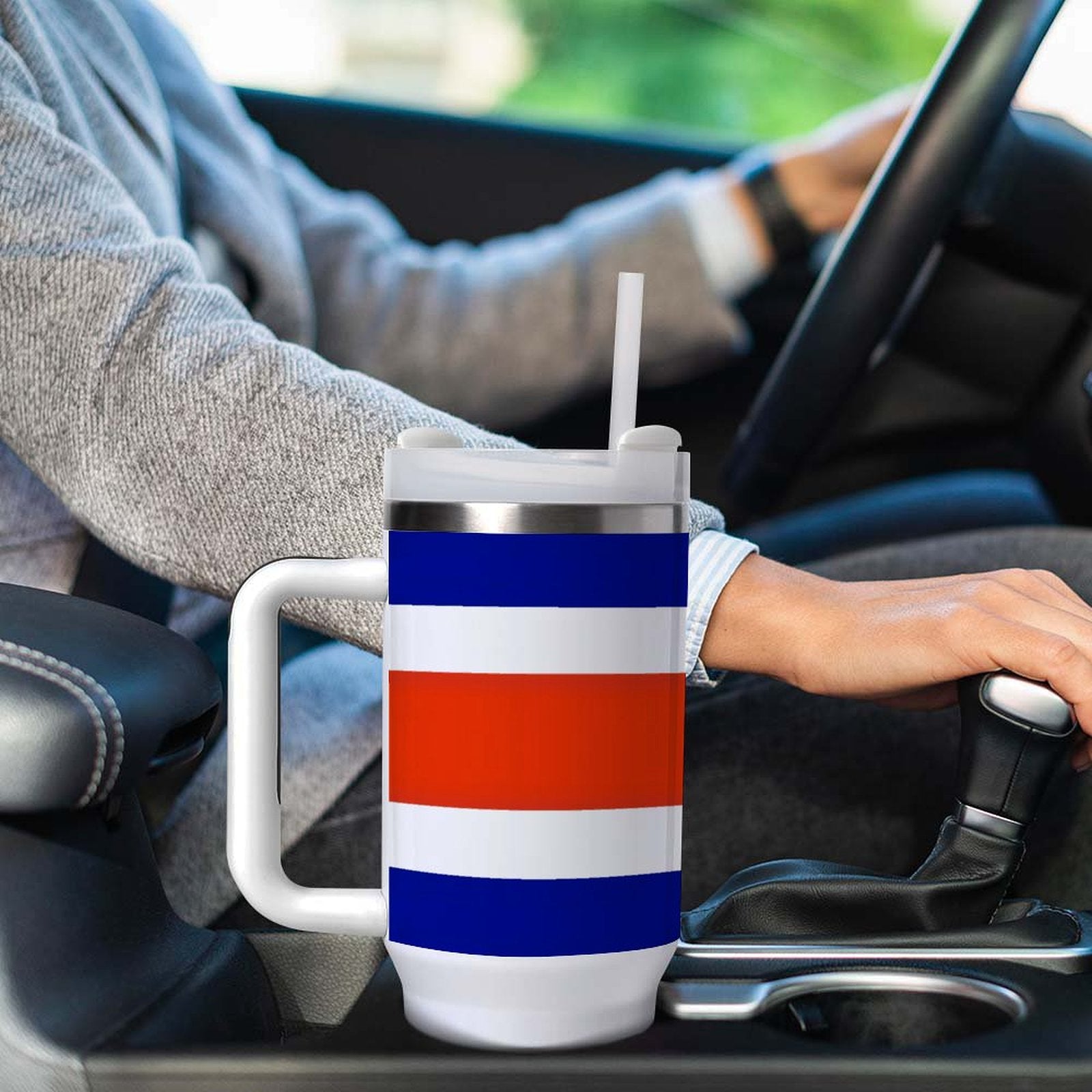 A [Brand] cup with straw in car cup holder.