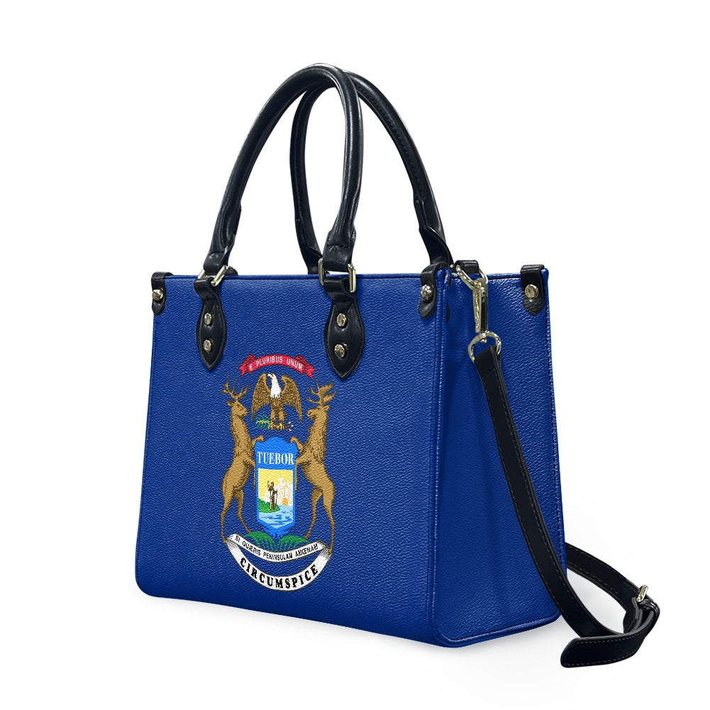 Blue handbag with Michigan seal, black handles, [Brand] design.