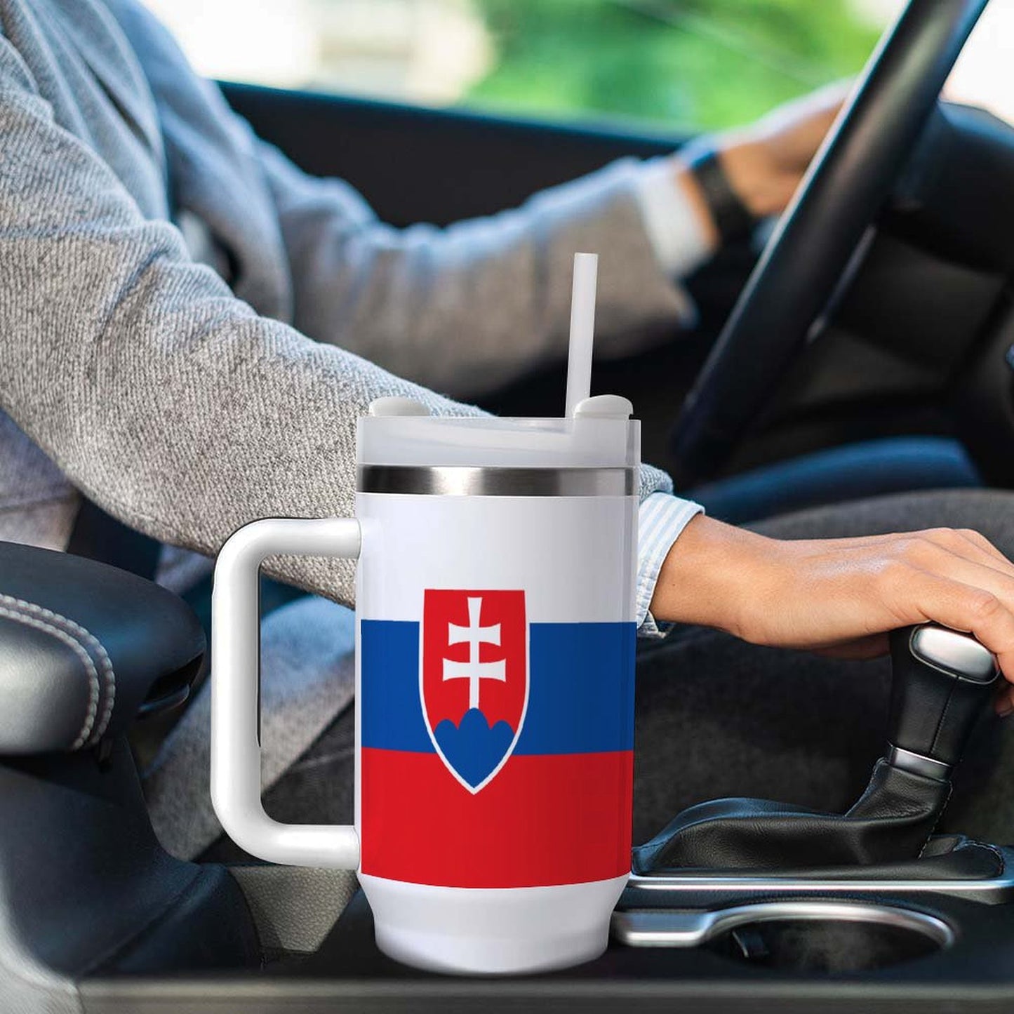 Driver holding gearshift beside [Brand] mug with Slovak flag.