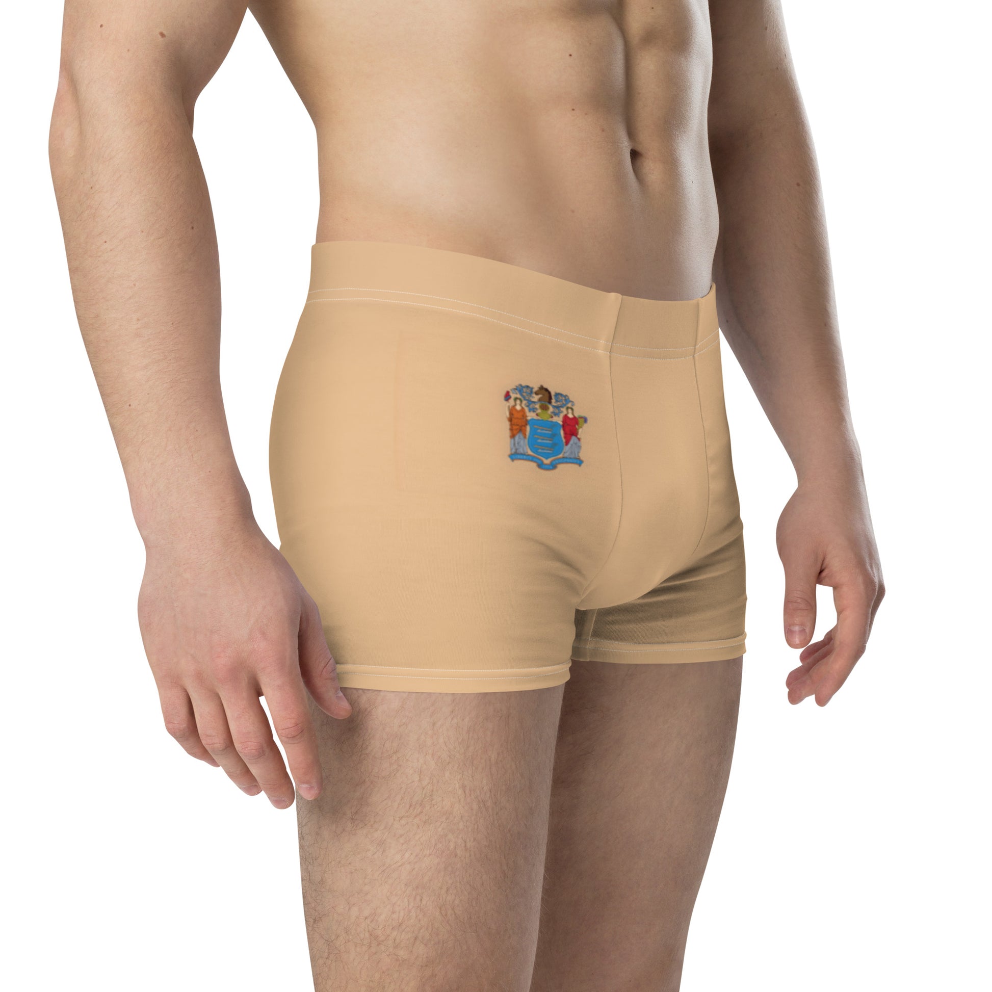 Man wearing tan [Brand] boxers with a colorful emblem.