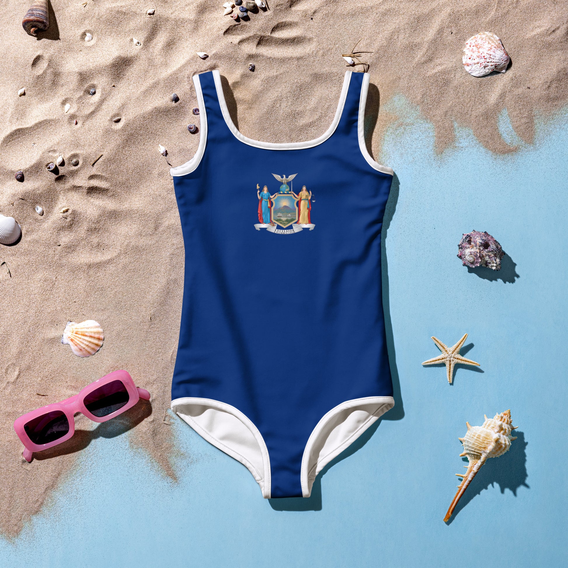 Navy [Brand] swimsuit on sandy beach with seashells, sunglasses.