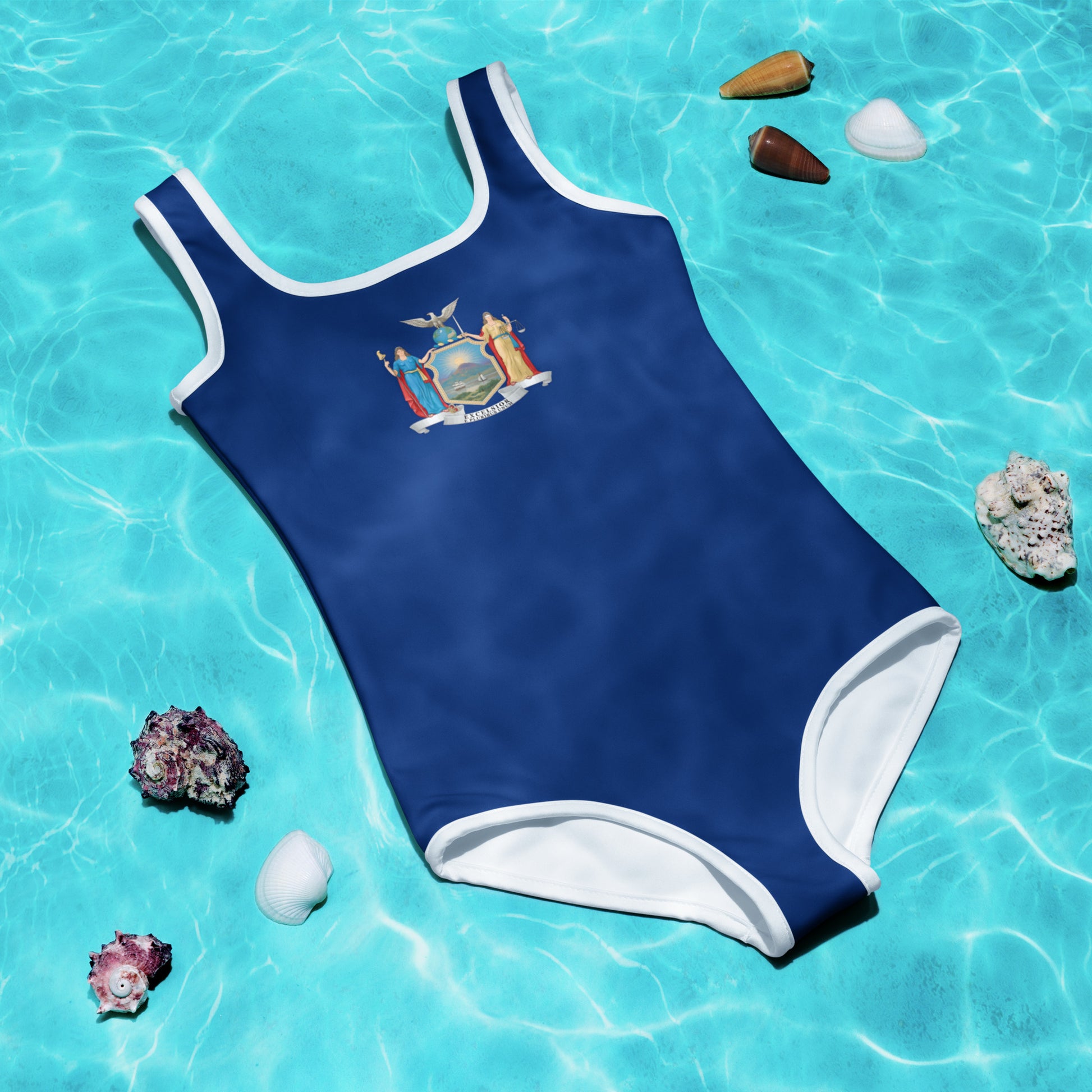 Blue [Brand] swimsuit floating in clear pool with shells.