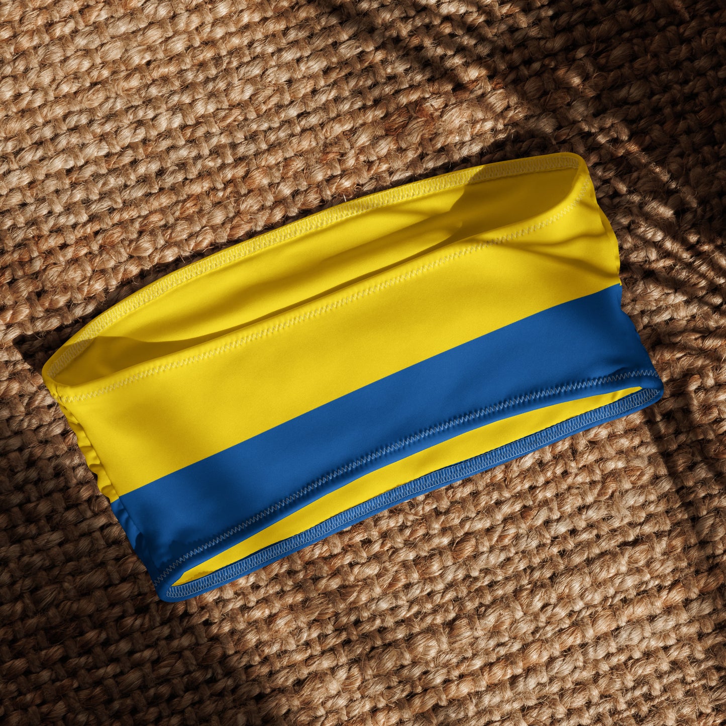 [Brand] yellow and blue striped garment on woven surface.