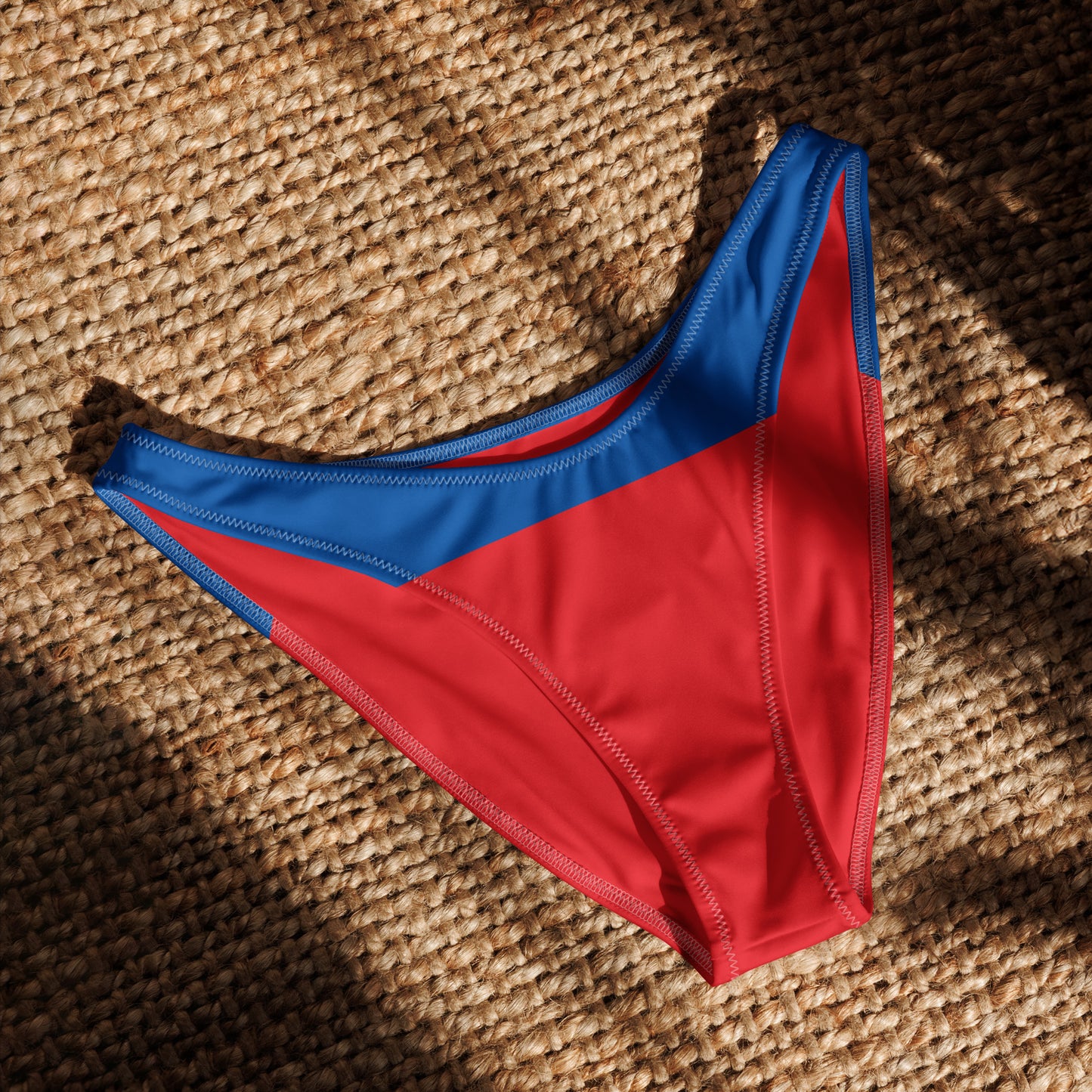 Red and blue [Brand] bikini bottom on woven surface.
