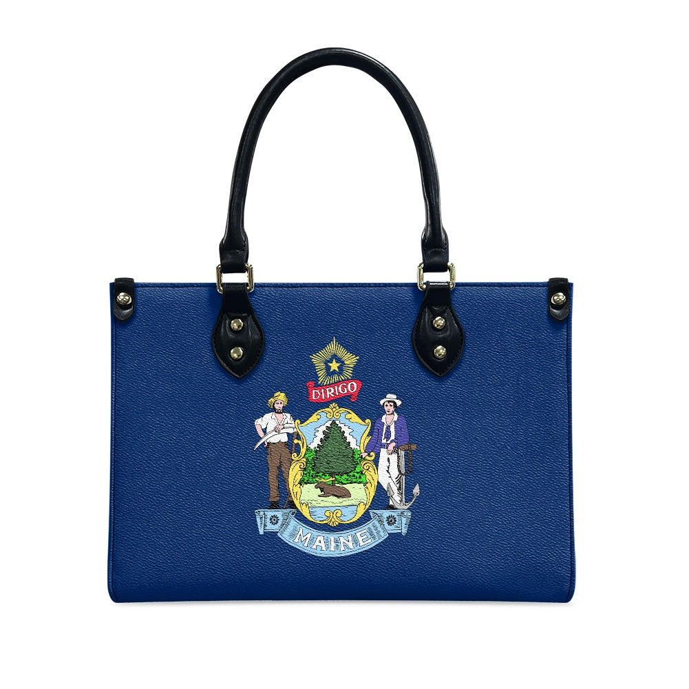 Blue handbag featuring Maine state emblem, black handles. [Brand]