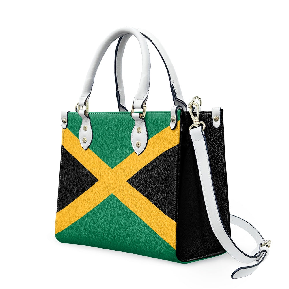 [Brand] handbag featuring Jamaican flag design with white handles.