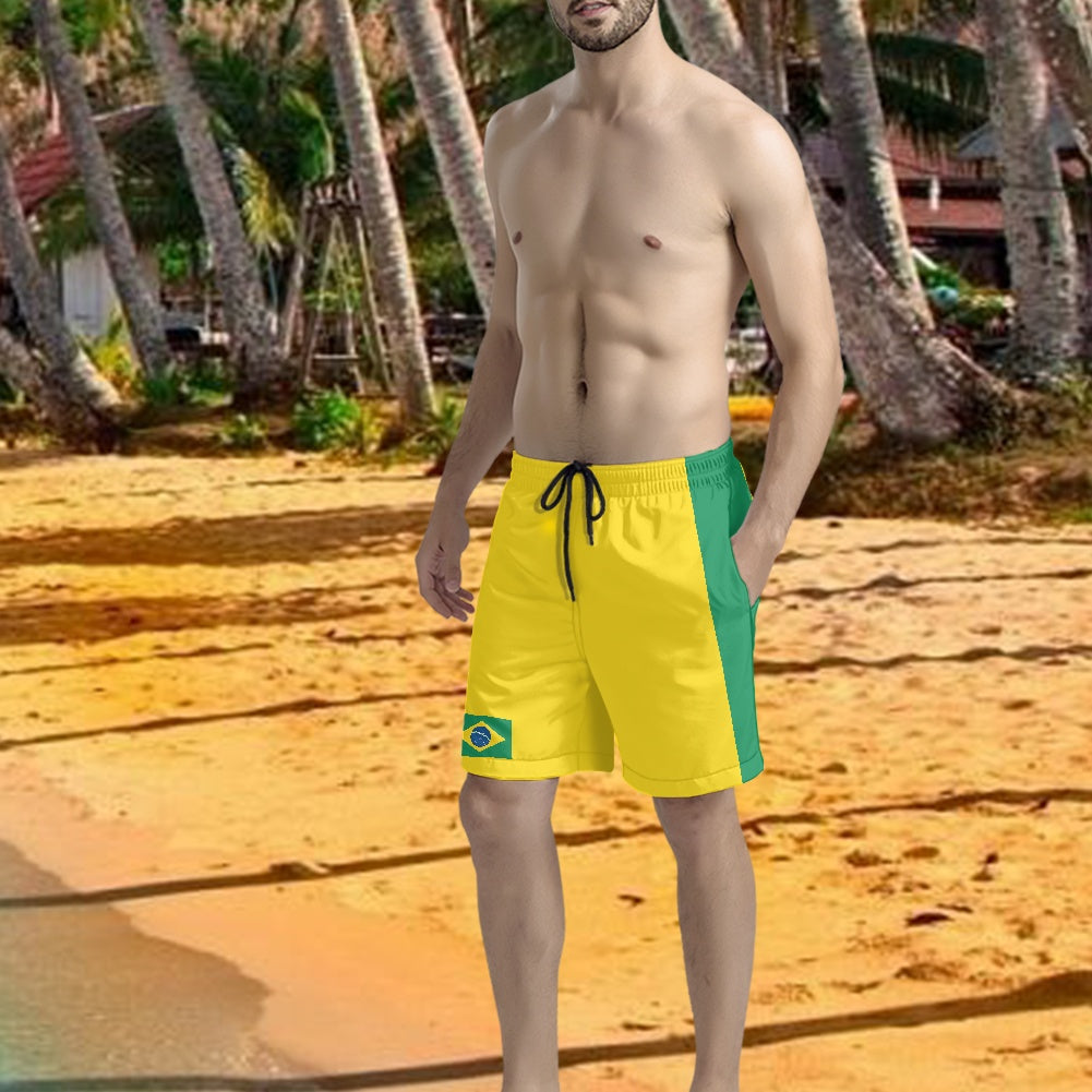 Brazil flag inspired yellow and green swim shorts with drawstring, modeled on a beach with palm trees in the background