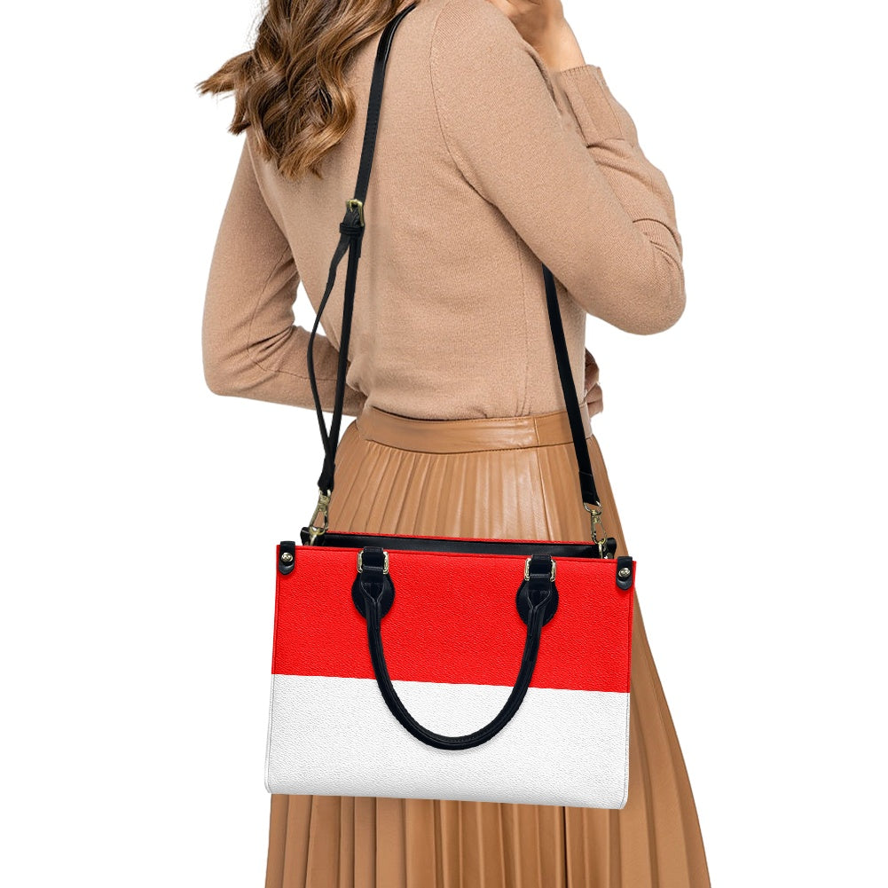 Woman holding [Brand] handbag with red and white design.