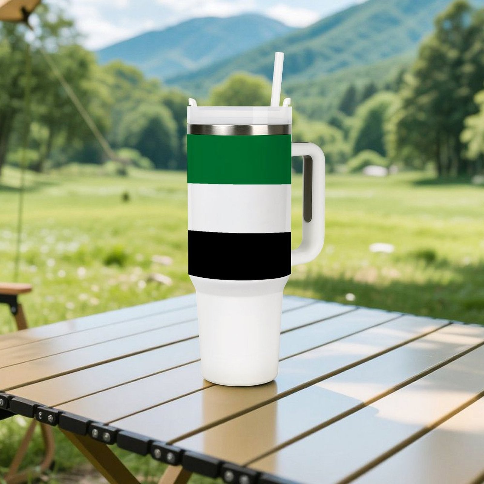 [Brand] travel mug on outdoor table, green landscape background.