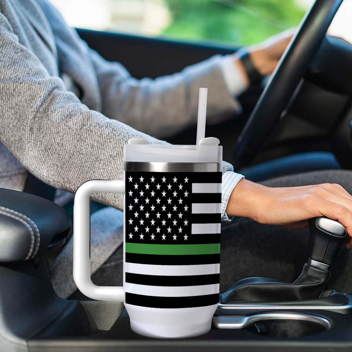Person driving holding [Brand] mug with green-striped flag design.