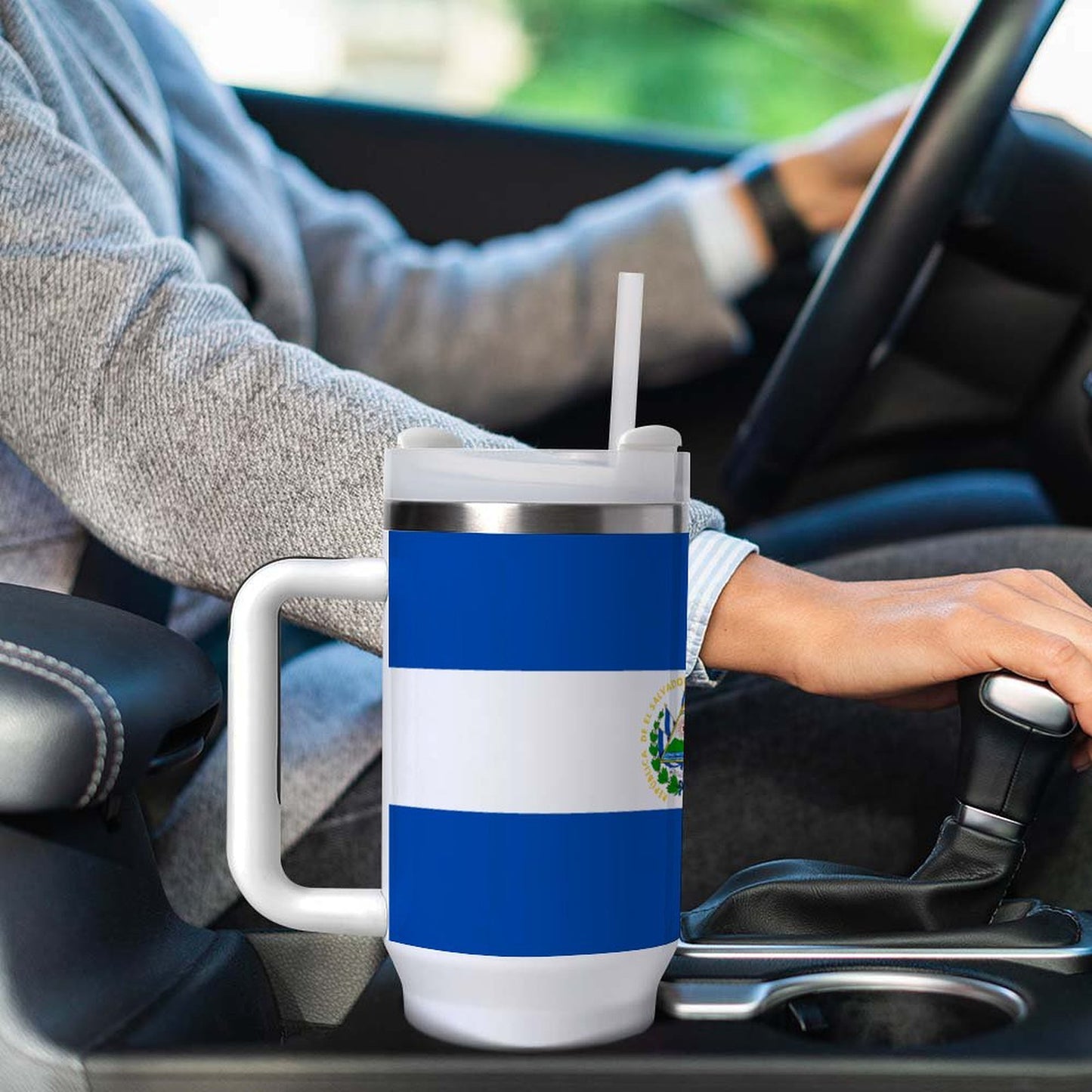Person driving car with [Brand] mug beside them, flag design.