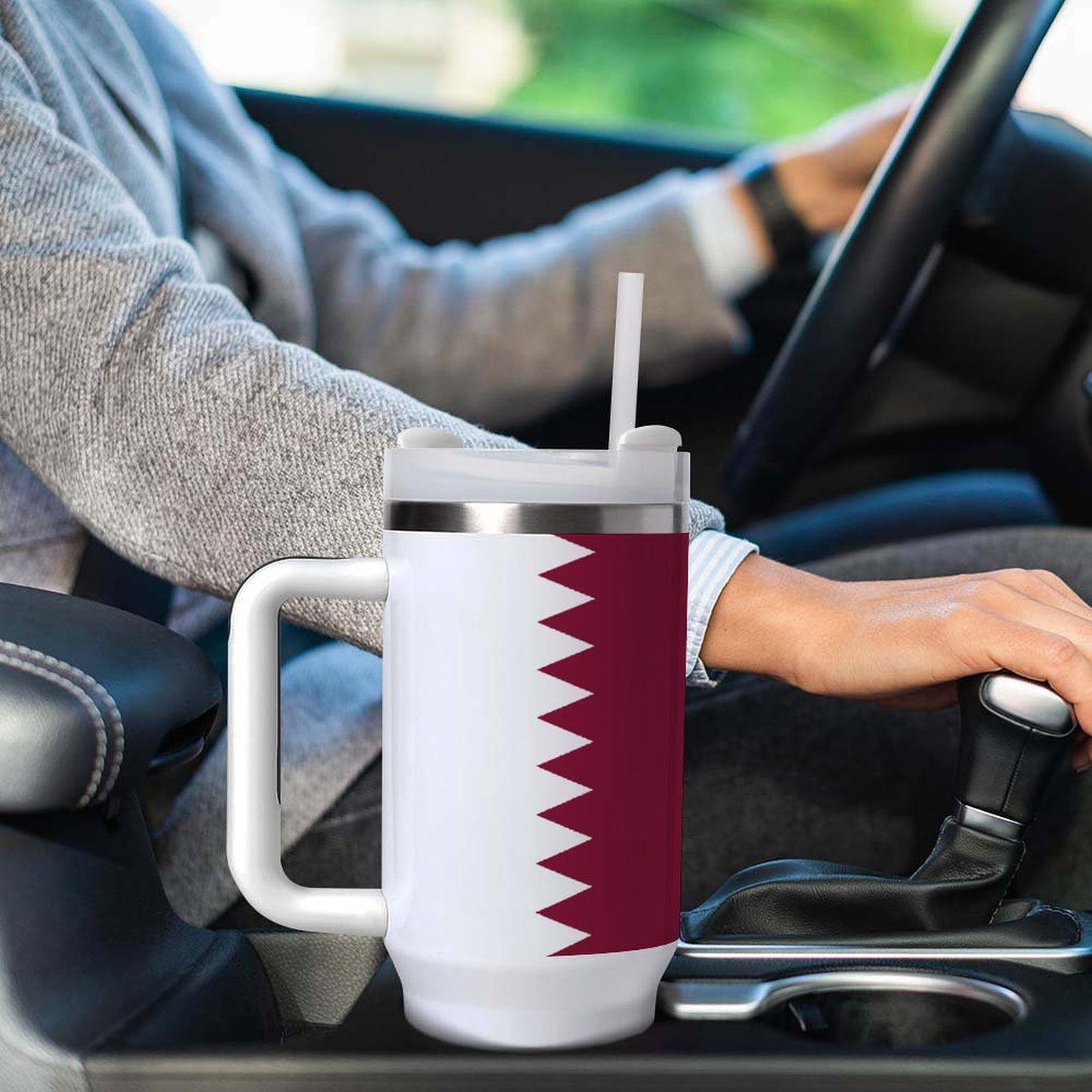 Driver holding [Brand] travel mug with Qatar flag design.
