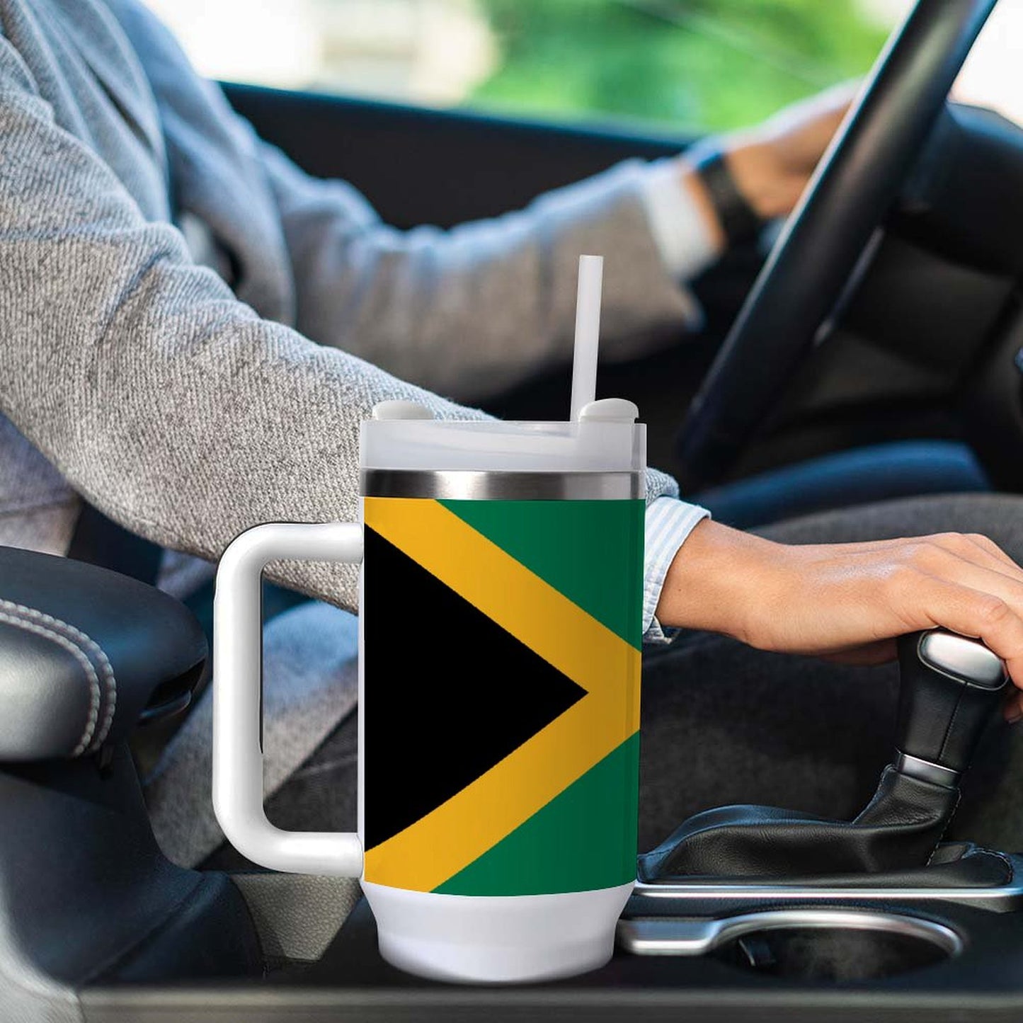 Person driving with [Brand] mug featuring Jamaican flag design.