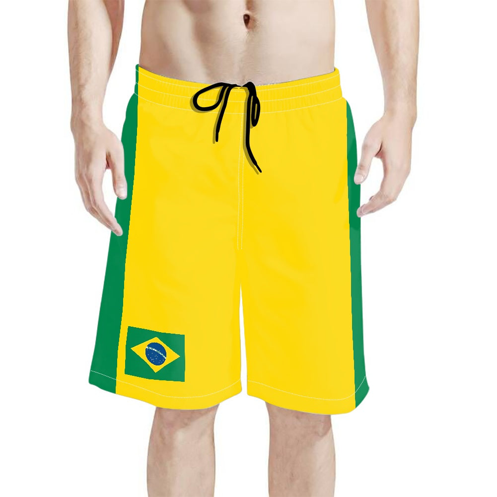 Yellow and green Brazil flag beach shorts with drawstring, shown on model against a white background