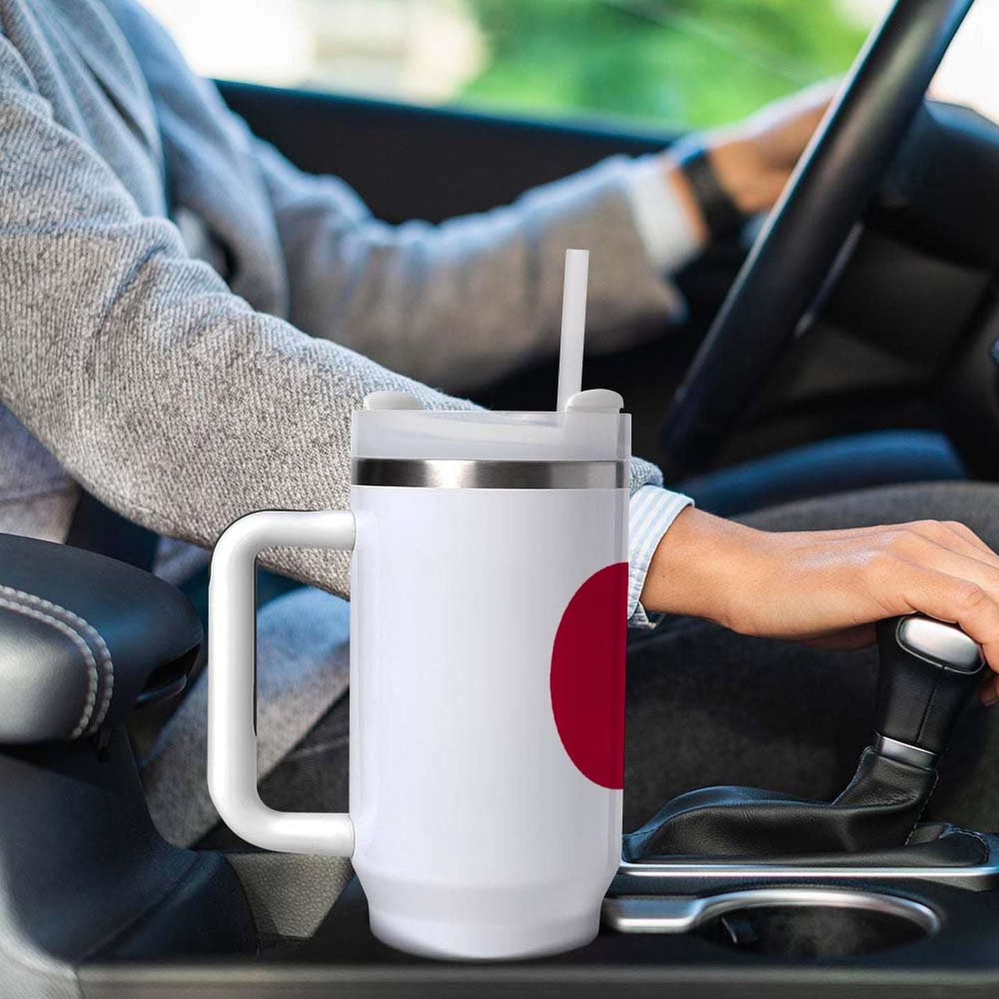Driver holds gear shift, [Brand] mug in car cup holder.
