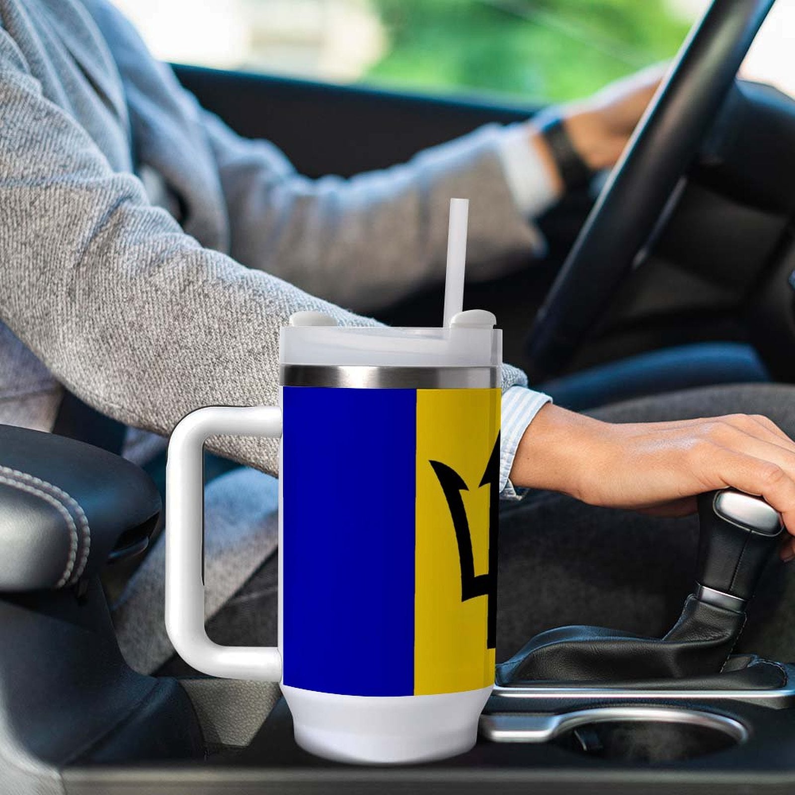 Driver holding gearshift with [Brand] travel mug in car.