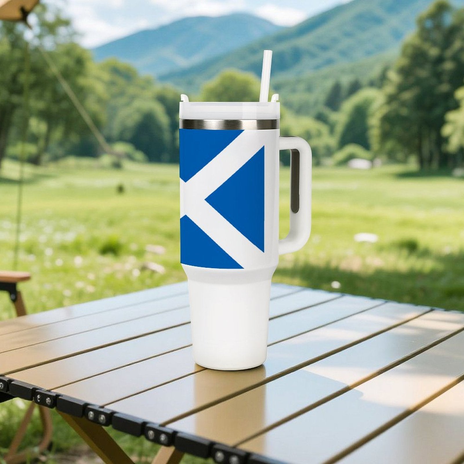 [Brand] travel mug with handle on outdoor table, mountains.