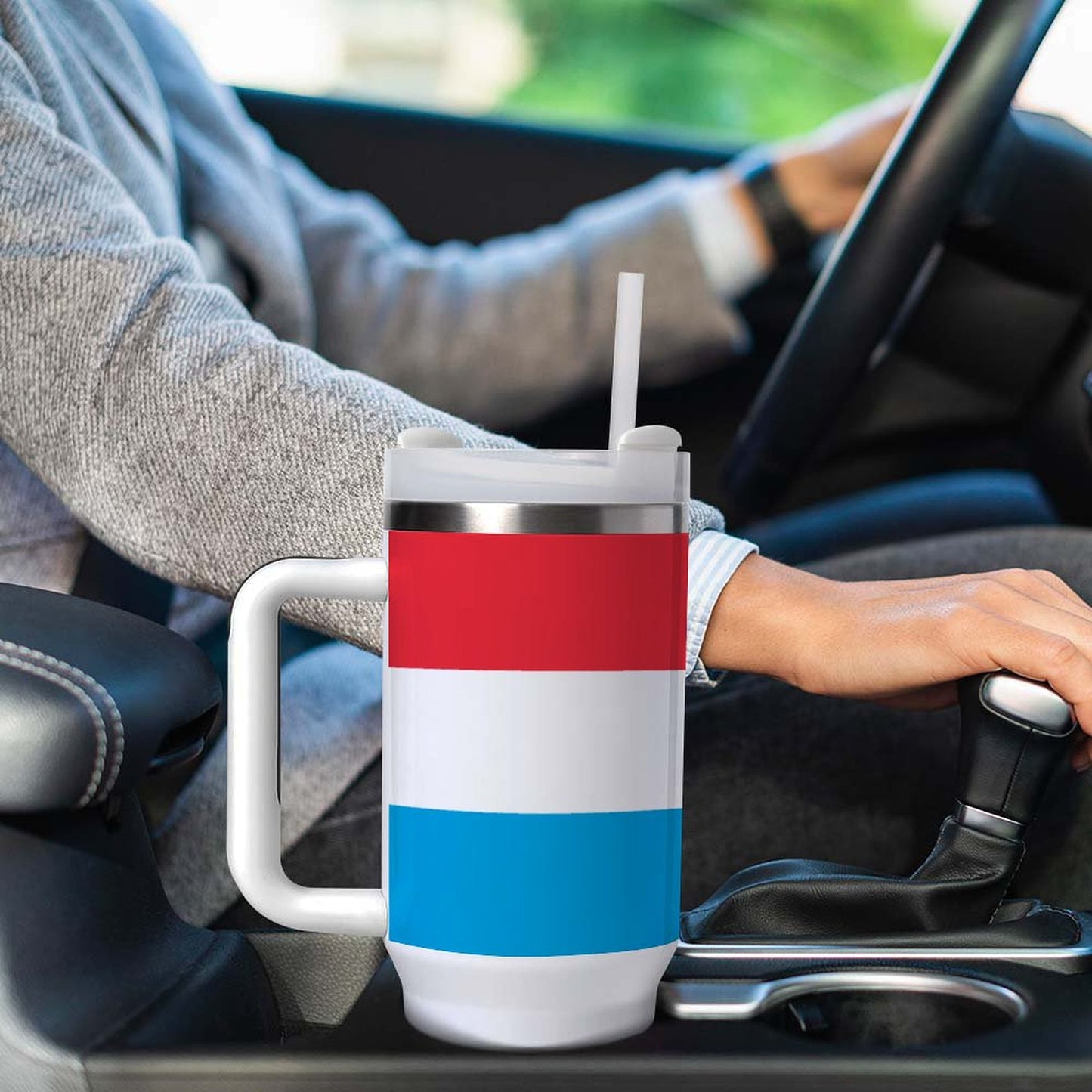 [Brand] striped travel mug in car’s cup holder, driving.