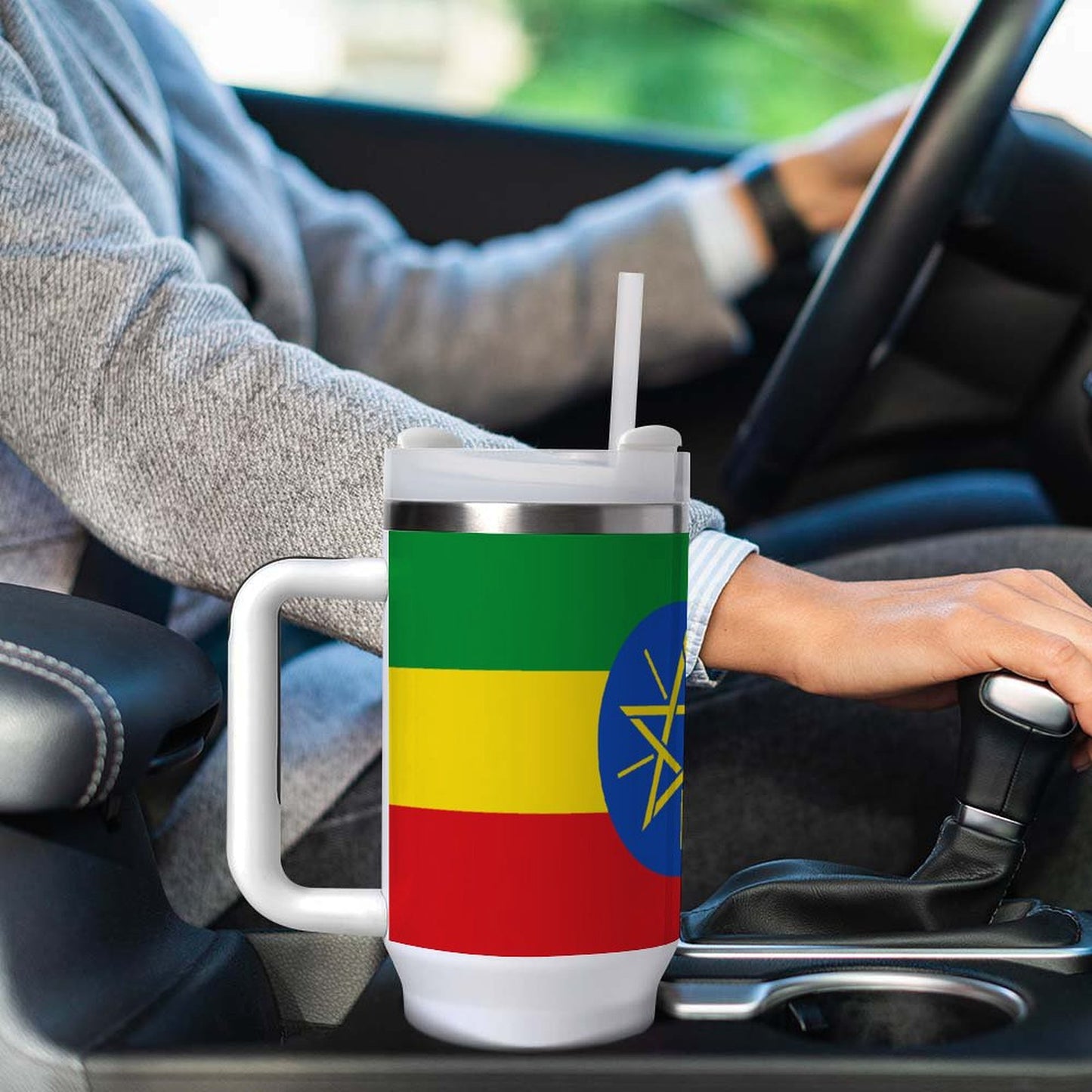 Person driving car with [Brand] Ethiopian flag-themed travel mug.