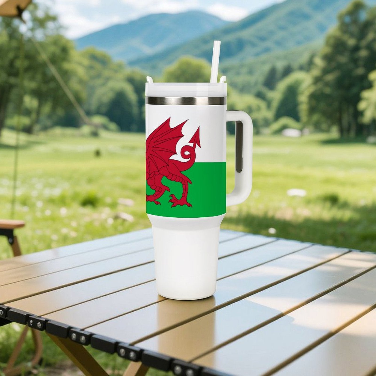 [Brand] travel mug featuring Welsh dragon design on table outdoors.