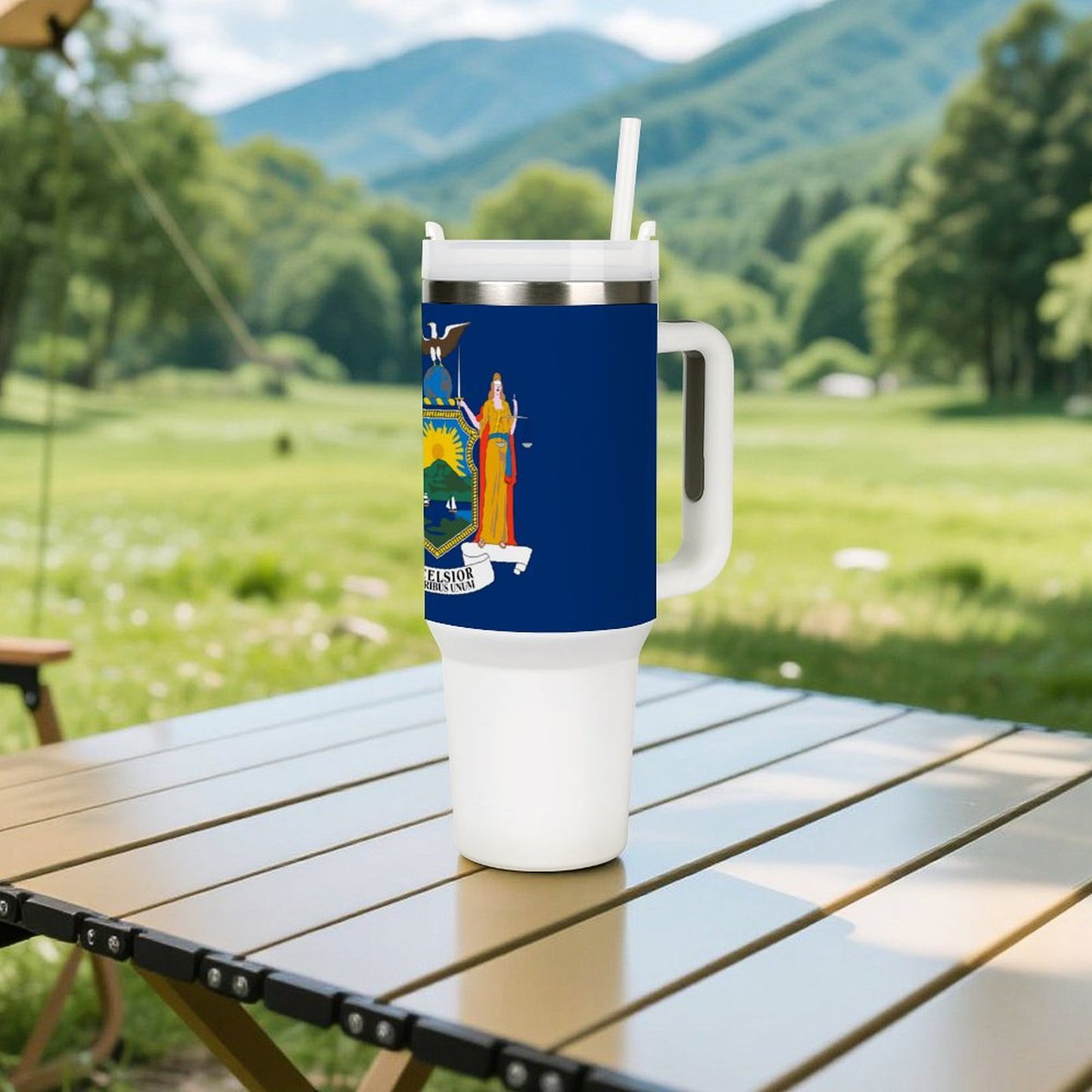 [Brand] insulated mug with straw on outdoor table, mountains.