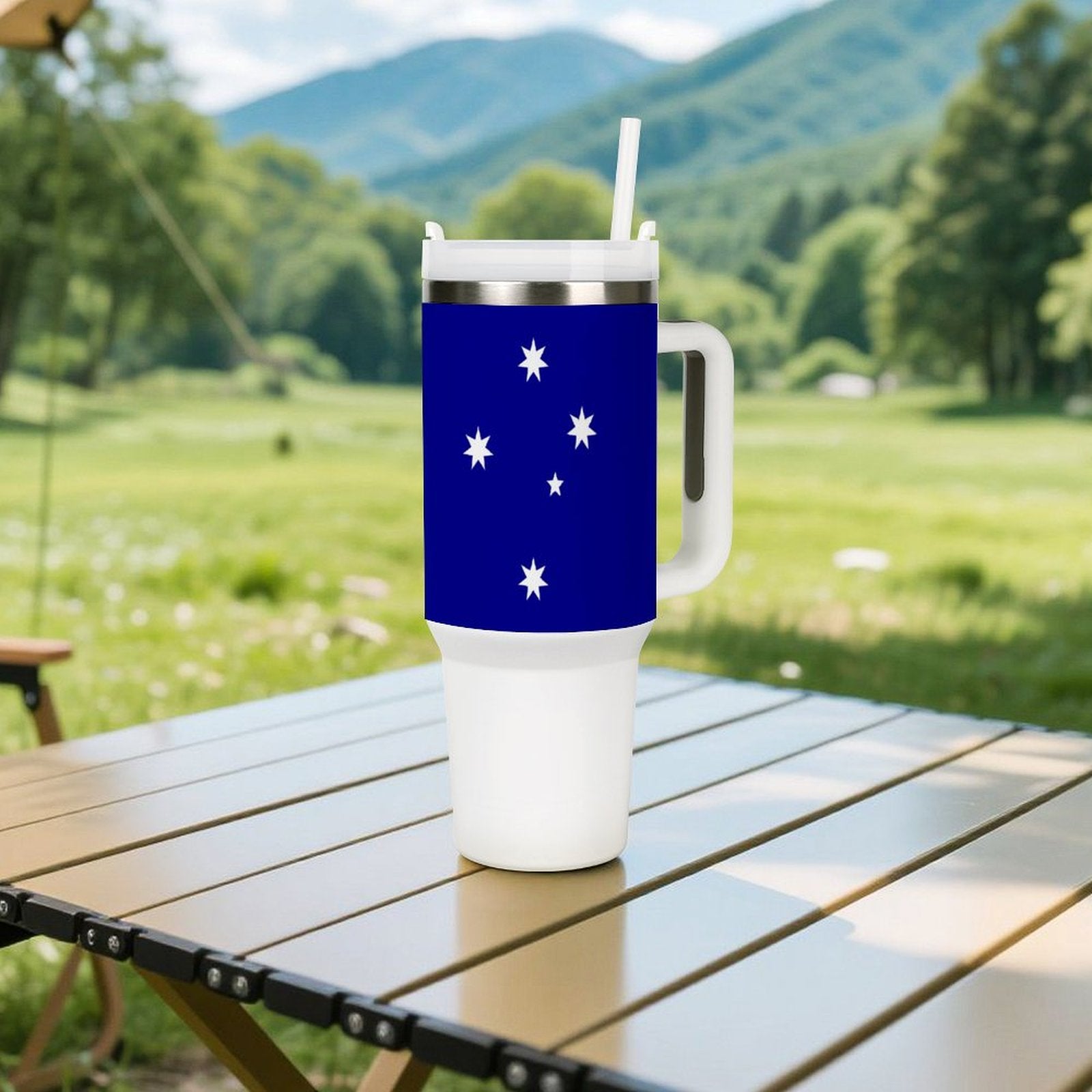 [Brand] tumbler with stars on table, scenic mountain background.