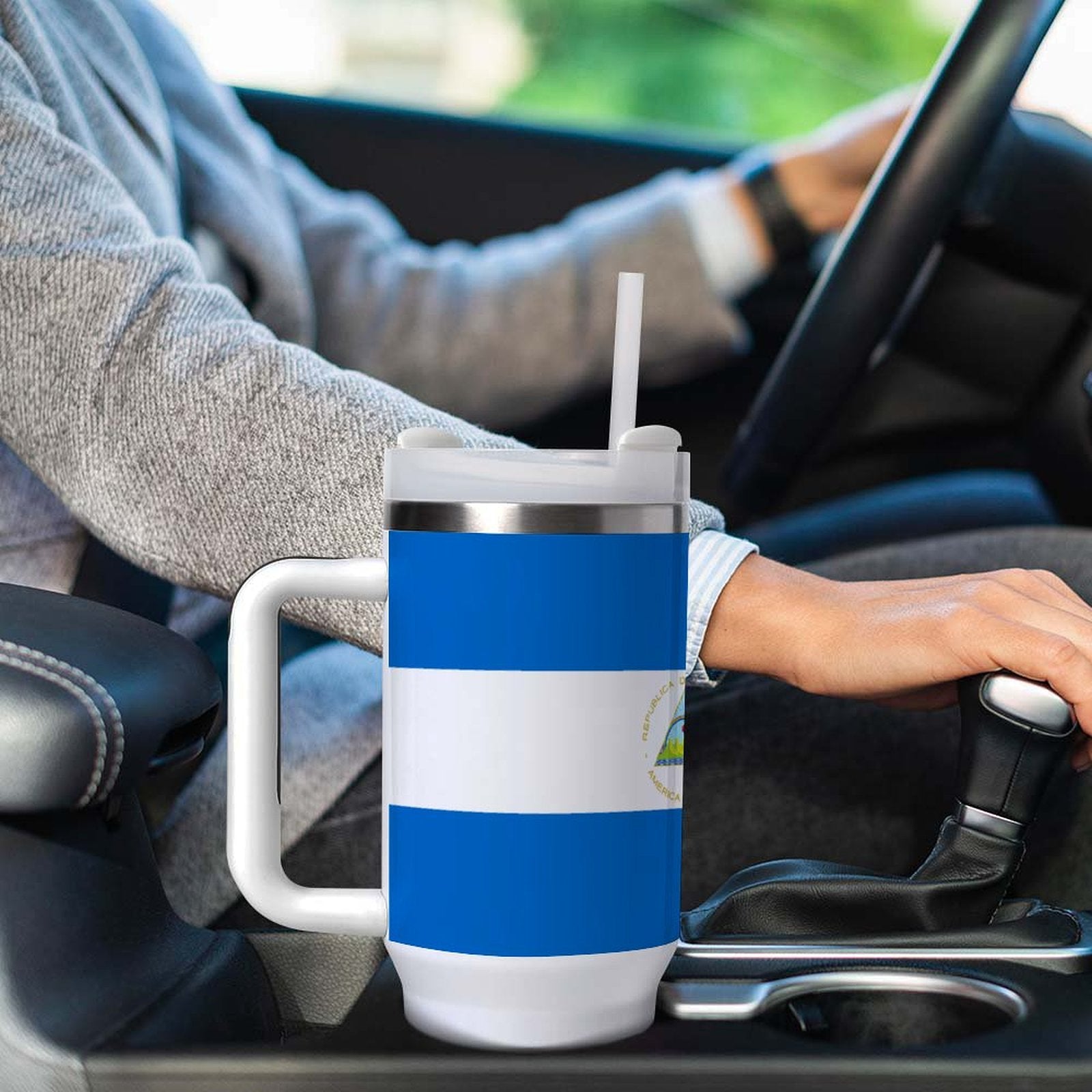 Person driving car with [Brand] travel mug in holder.