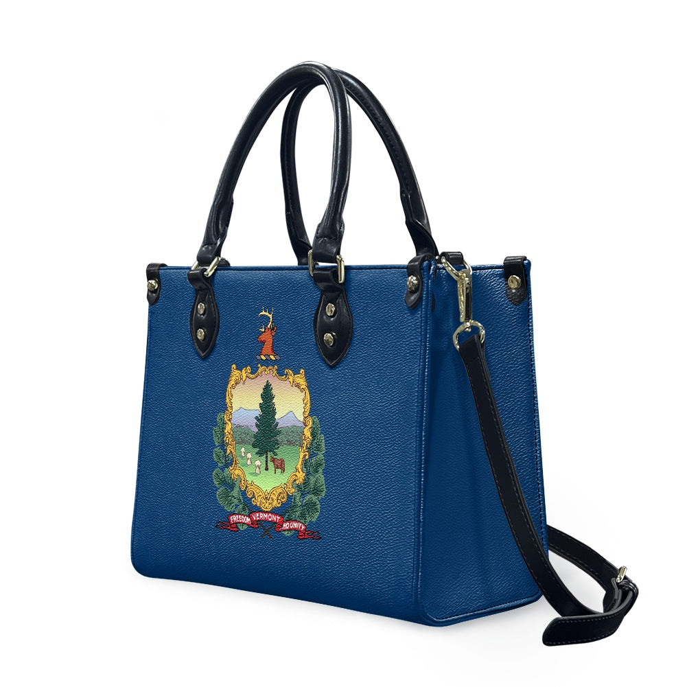 Blue handbag with Vermont emblem; [Brand] design, black handles.