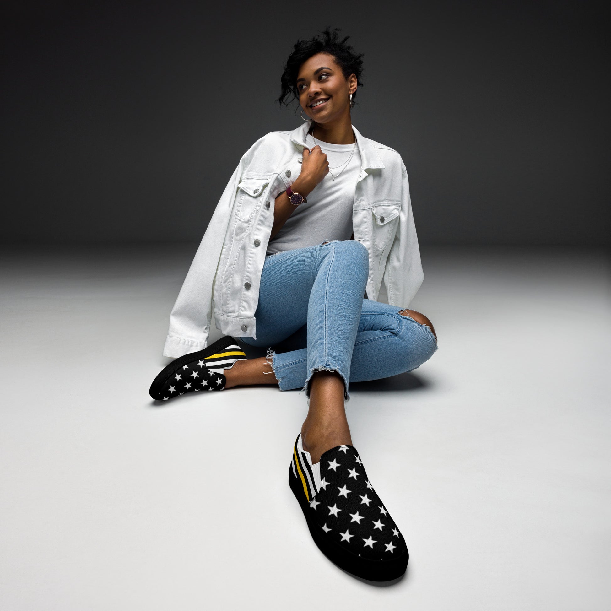 Person wearing Brand star-patterned shoes, white jacket, blue jeans.